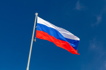 The national flag of Russia is under blue sky