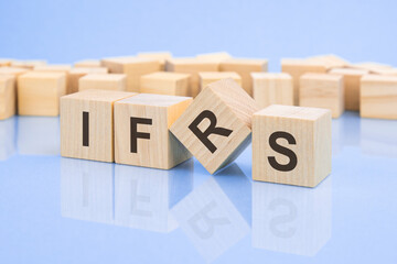 wooden cubes with the letters IFRS the bright surface of a pale lilac table. the inscription on the cubes is reflected from the surface of the table. business concept