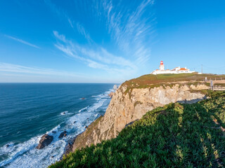 Fototapeta na wymiar Cabo da Roca cliffs and lighthouse on the coast of the Atlantic ocean with stunning waves, the westernmost point of Europe, Portugal