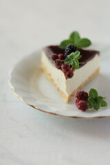  A slice of cheesecake decorated with mint leaves and berries on white plate with golden rim, minimalist concept on white background, traditional American dessert.