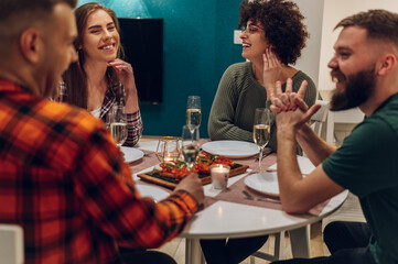 Group of friends enjoying dinner while sitting at the kitchen table together