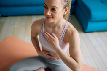 Woman siting in a lotus yoga position on the fitness mat at home