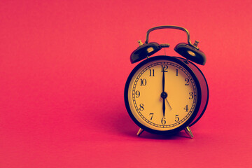 vintage old black alarm clock on pink background