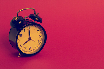 vintage old black alarm clock on pink background	