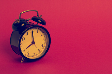 vintage old black alarm clock on pink background