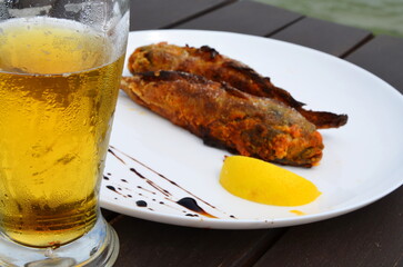 beer in a glass goblet on the background of fried fish with lemon