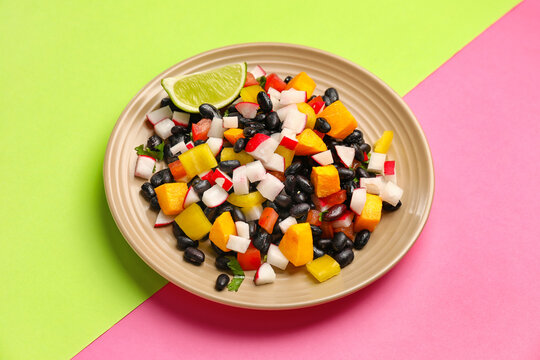 Plate of tasty Mexican salad with radish and black beans on color background