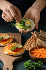 Woman making tasty sandwich with healthy hummus at table