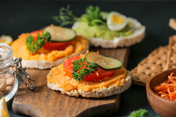 Crispbreads with tasty hummus on wooden board