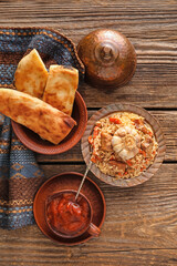 Plate of traditional pilaf with tomato sauce and flatbread on table