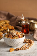Bowl with tasty pilaf and tasbih on table