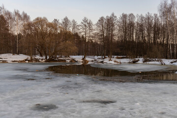 Early spring landscape. Melting snow and thawed patches in forest at sunset. Spring concept. Thawed patches.