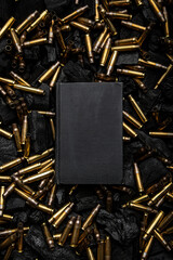 Cover of a black closed book. Empty gun cases lying on charred coals. Dark back.