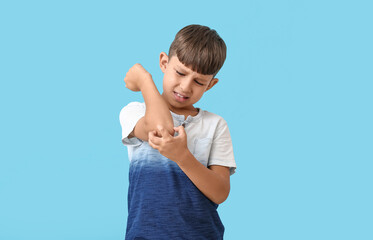 Little boy scratching himself on color background
