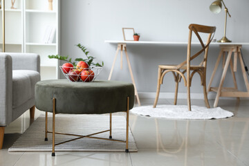 Bowl with apples on pouf in light living room