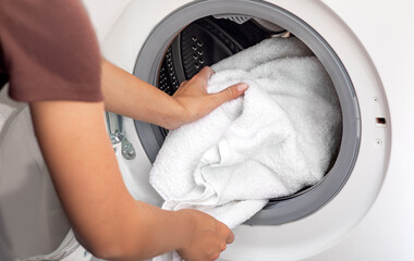Woman loading laundry to the washing machine
