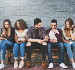 Whats life without friends and wifi. Shot of a group of young friends using their mobile phones...
