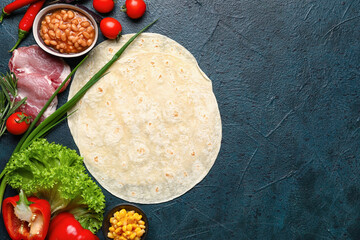 Tortillas and fresh ingredients for preparing tasty burrito on dark background