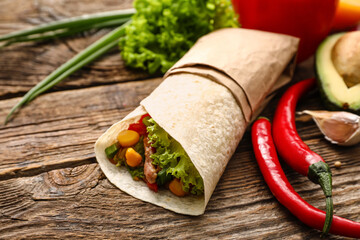Tasty burrito with meat on wooden background