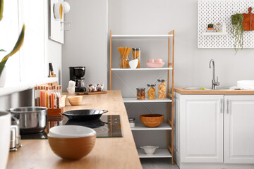 Stylish counter with dishware and modern shelving unit in kitchen