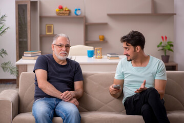 Father and son watching tv during pandemic