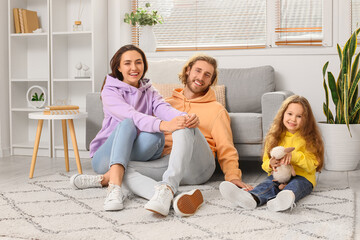 Young family sitting on soft carpet at home