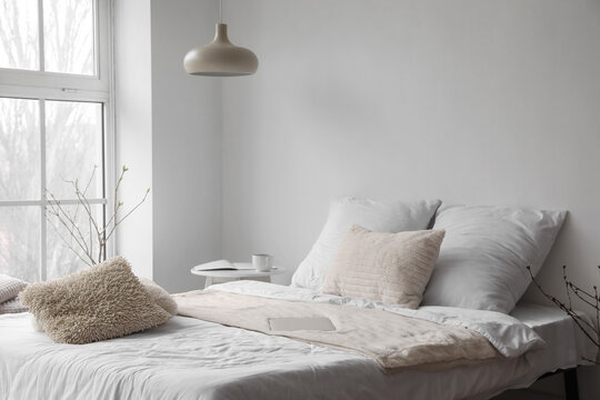Modern laptop on bed near white wall in light room