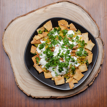 Egyptian traditional food, Fatta, rice, chicken, yogurt and roasted bread pieces, in black plate, on wooden log, homemade
