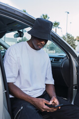 Black manan sitting in a car with an open door.