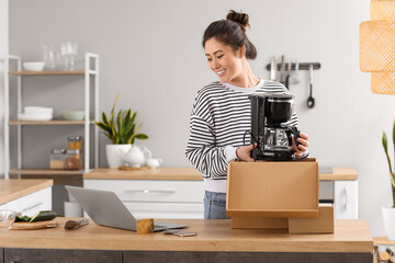 Happy young woman with new coffee maker at home. Online shopping
