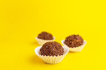 Three Brazilian Brigadeiros on a yellow background with copy space.
