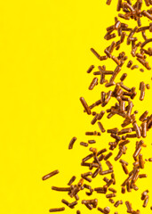 Chocolate sprinkles falling down with yellow background