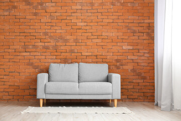 Stylish sofa near brick wall