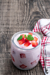 Homemade strawberry yogurt with fresh sliced berries on wooden table