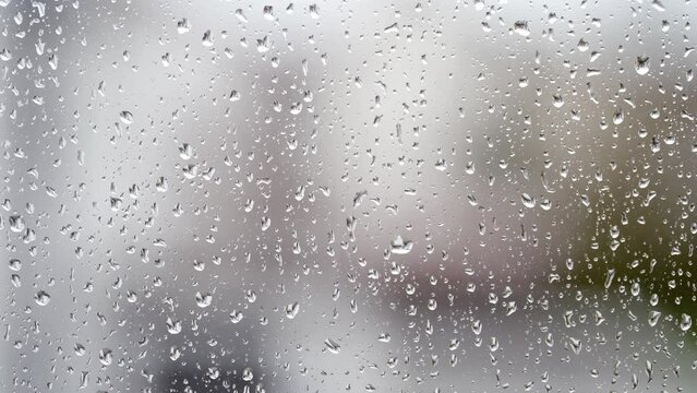 Close-up of water droplets on glass. Large rain drops strike a window pane. 4K.