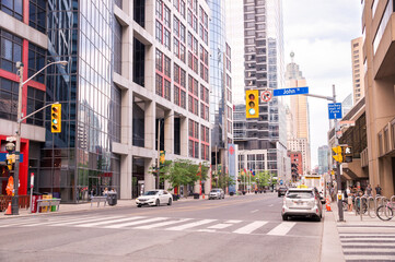 Obraz na płótnie Canvas TORONTO, CANADA - 06 05 2021: Sunny summer day view along Front Street in downtown Toonto with glassy skyscrapers and spire of TD Canada Trust Tower in background