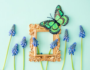 Spring creative look with a butterfly, flowers and a gold picture frame on a background of blue sky. Retro romantic aesthetic summer concept of the 80's, 90's. Minimal surreal idea.