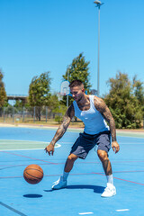 Sporty Caucasian male with tattoos playing basketball