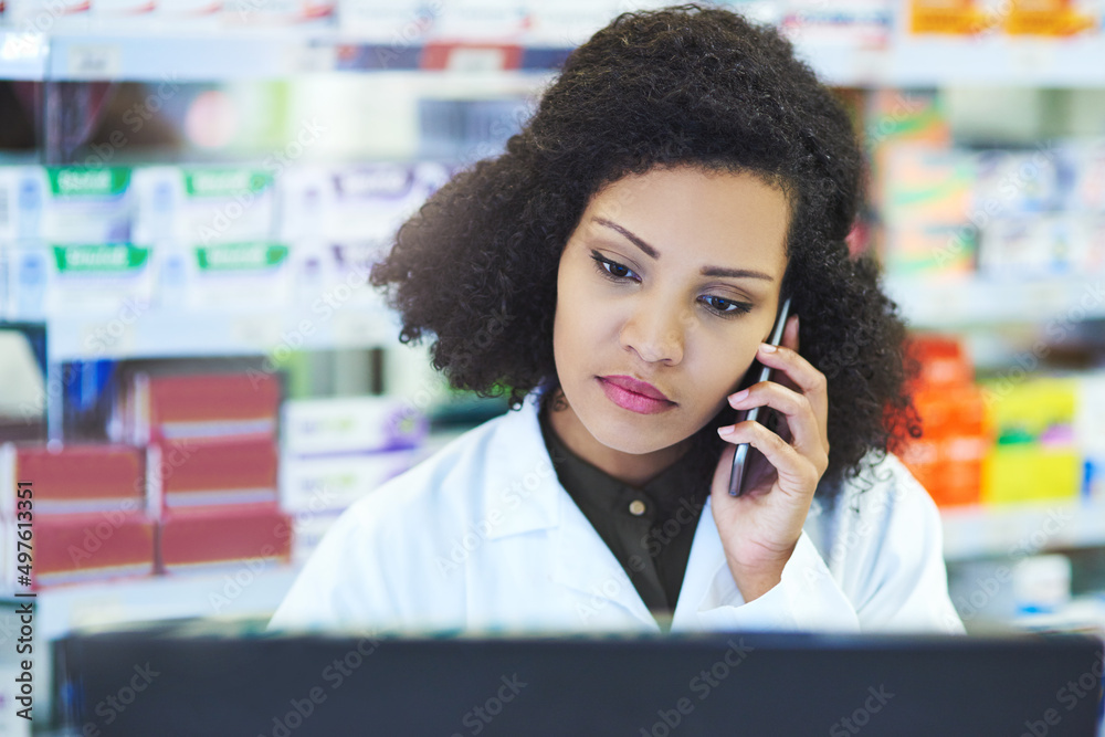 Poster Let me see if we have it at this branch. Shot of a young woman using a computer and mobile phone at the counter of a pharmacy.