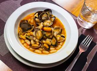 Shellfish in a plate with white beans on table in restaurant, nobody..