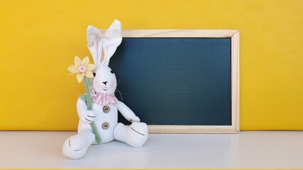 Decorative blackboard with Easter bunny in the front with yellow background. Space for text.
