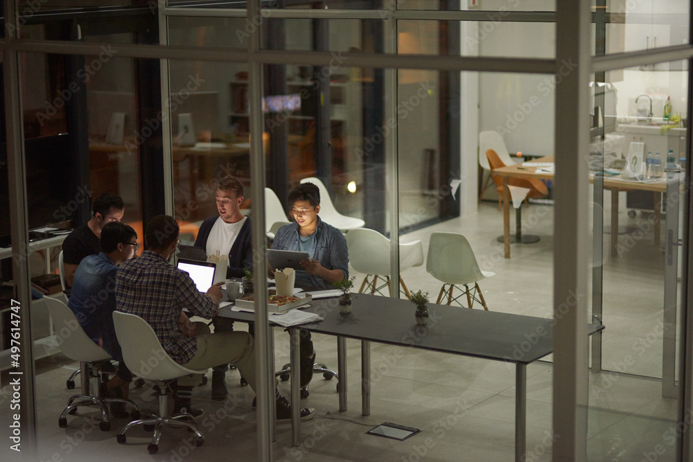 Aufkleber putting in some extra hours at work. shot of employees working in an office at night.