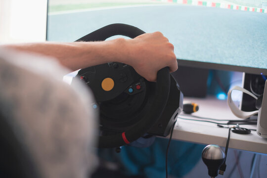 person improving his driving skills, race simulator with steering wheel and pedals
