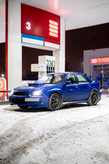 blue car at night on the fuel gas station in the winter