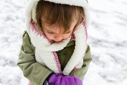 Close-up of toddler girl in winter gear playing outside in snow