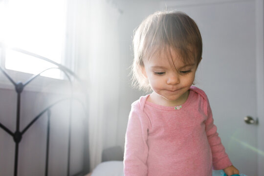 toddler girl stands on bed