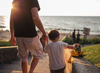 father and son walk to beach holding hands