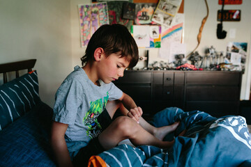 boy sits quietly on bed in his room