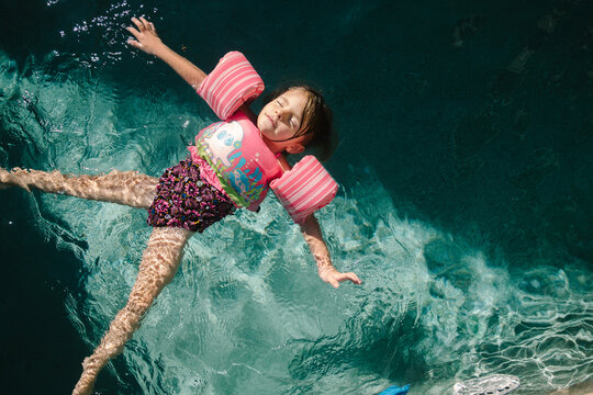 little girl floating on back in swimming pool 
