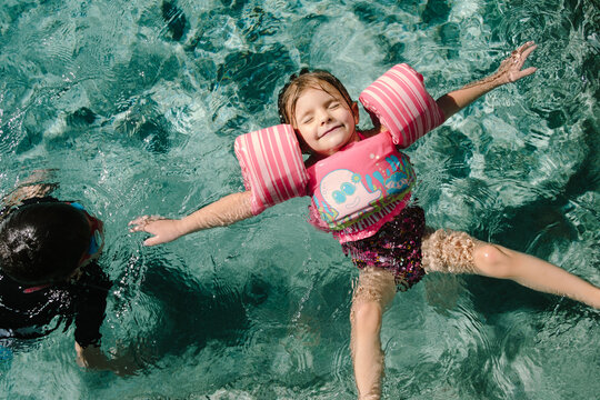 little girl floating on back in swimming pool 
